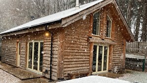 A wooden cabin with a sloped roof, large windows, and a chimney. - Secluded, rural retreat nestled in Sherwood Forest, with hot tub (Newark)