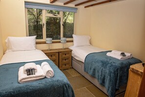 A bedroom with two beds, a nightstand, and a window with blinds. - Secluded, rural retreat nestled in Sherwood Forest, with hot tub (Newark)
