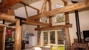 A rustic interior with exposed wooden beams, a fireplace, and a dining area with outdoor views. - Secluded, rural retreat nestled in Sherwood Forest, with hot tub (Newark)