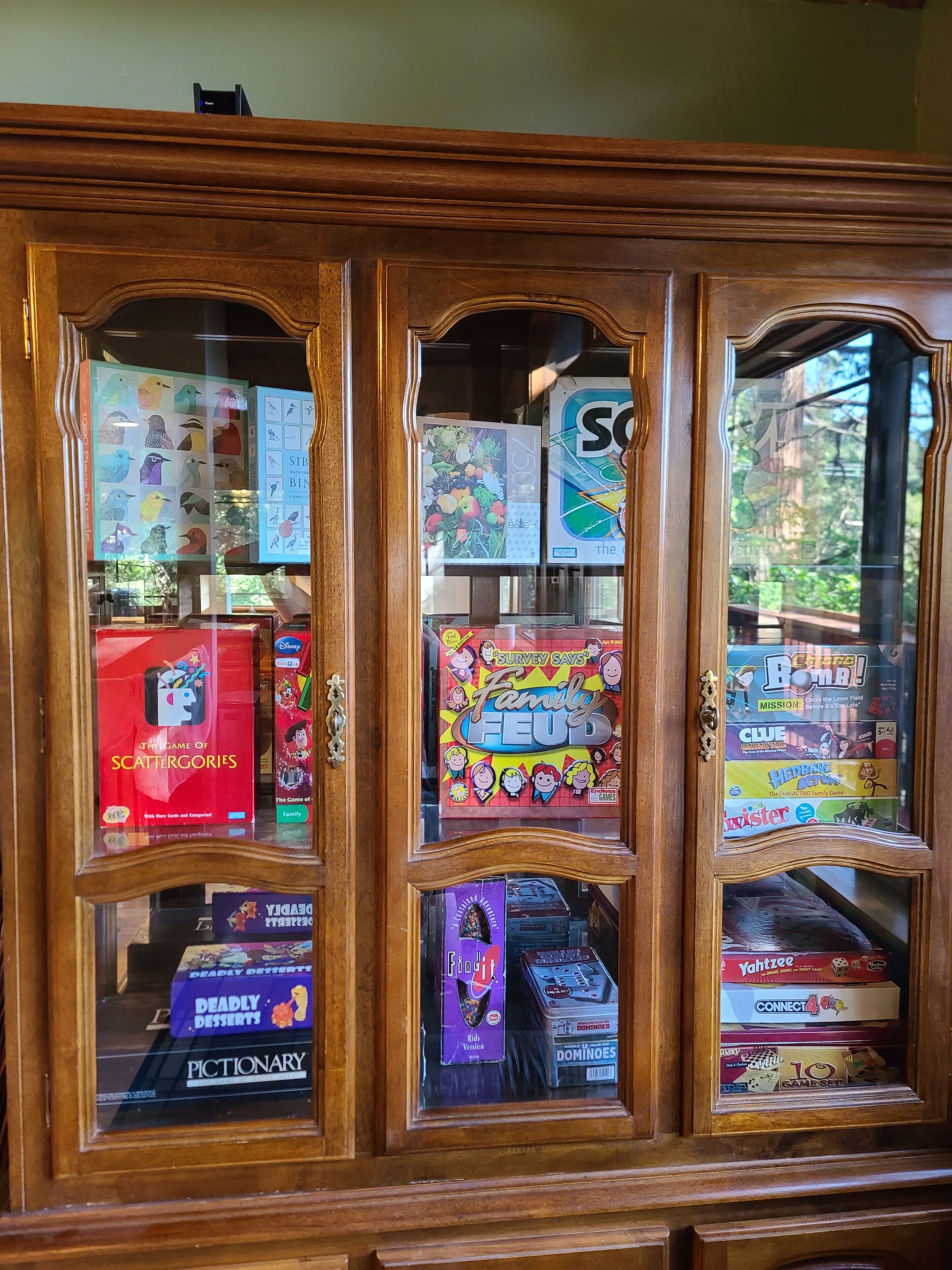 A wooden cabinet with glass doors displaying various board games.