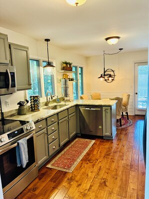 A modern kitchen with stainless steel appliances, a dishwasher, and a wooden floor. - Direct Lakefront Connestee Falls: Views + private dock + 4 kayaks + Not steep! (Brevard)