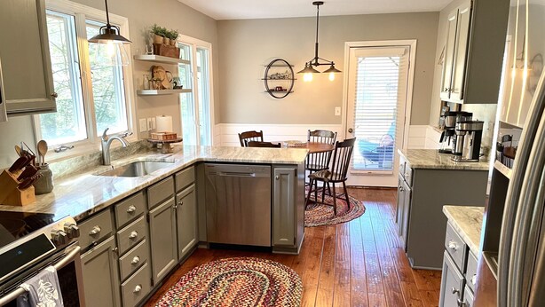 A modern kitchen with a dishwasher, stove, and wooden flooring. - Direct Lakefront Connestee Falls: Views + private dock + 4 kayaks + Not steep! (Brevard)
