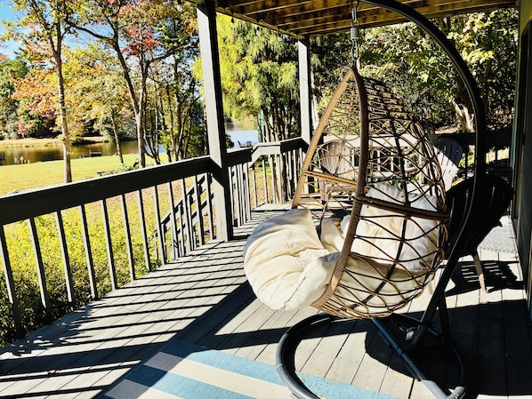 A wooden deck with a wicker swing chair and a bicycle.