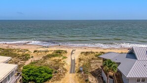 A beach with a paved path leading to the shore, surrounded by vegetation and buildings. - EdiStar at Edisto Beach (Edisto Beach)