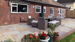 A brick house with a patio, outdoor furniture, and potted plants.