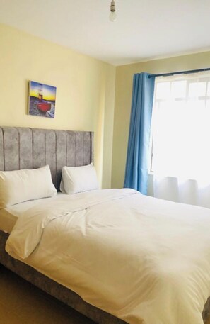 Relax in a serene space with a large bed and a beautiful painting of a boat above.