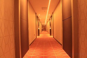 Un long couloir étroit, avec un sol et des murs décorés de motifs, qui mène à une porte au bout.
