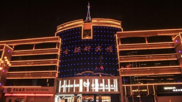 Un edificio de varios pisos con señalización iluminada y un llamativo rótulo del Banco de China en la planta baja.