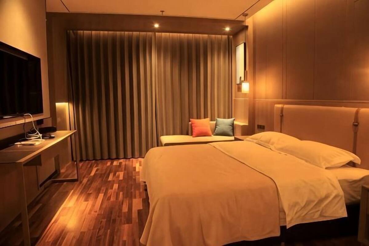Una habitación de hotel con cama, escritorio, televisor y cortina.