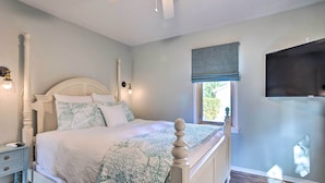 Une chambre à coucher comprenant un lit, une table de chevet, un téléviseur fixé au mur et une fenêtre donnant sur un paysage agréable.