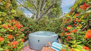 Un bain à remous entouré d’une végétation luxuriante et de fleurs aux couleurs vives.