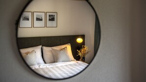 A bedroom with a bed, pillows, a nightstand with a lamp, and three framed pictures on the wall.