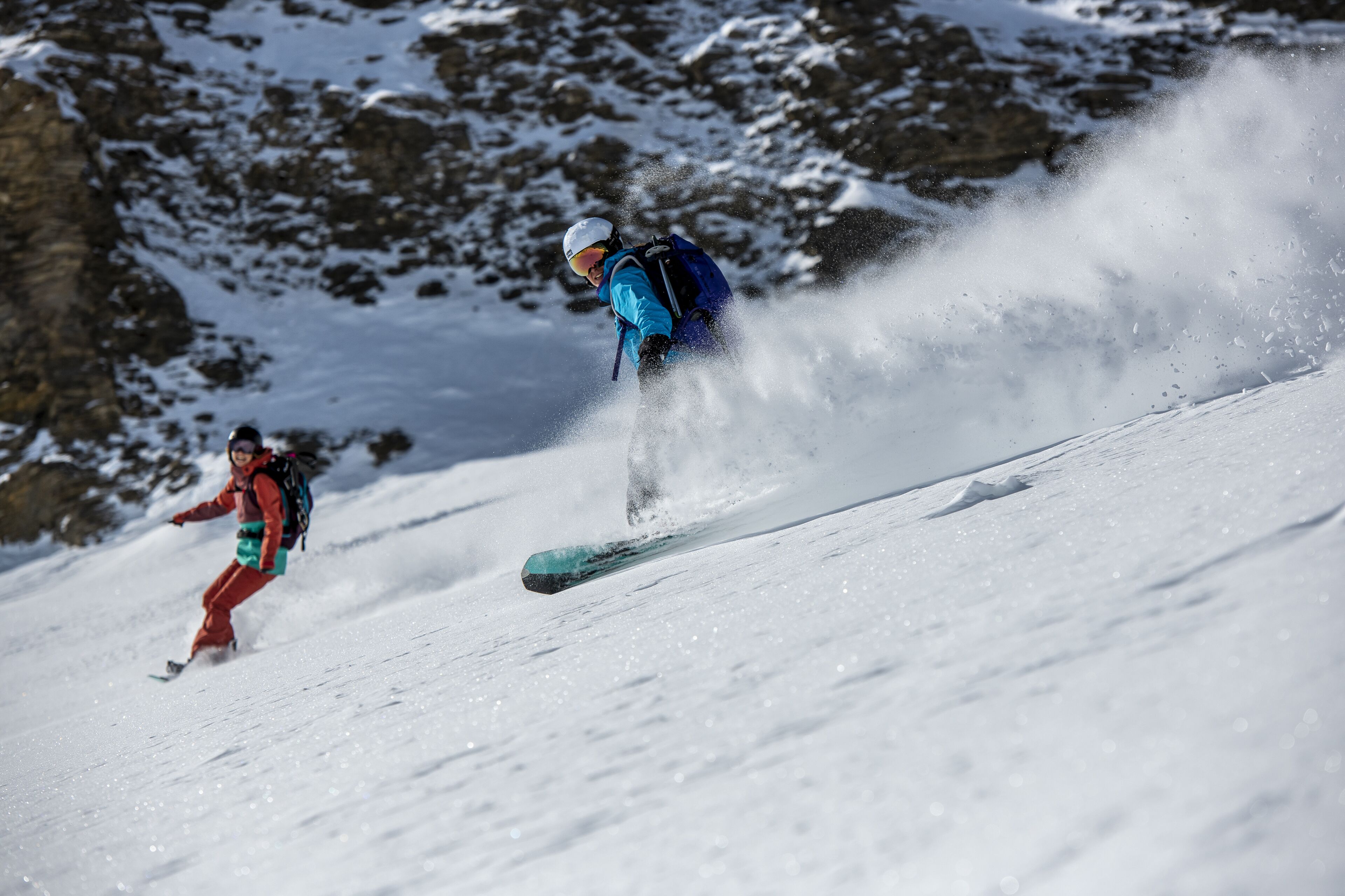 A person skiing down a snowy slope with a clear view of the surrounding rocky terrain.
