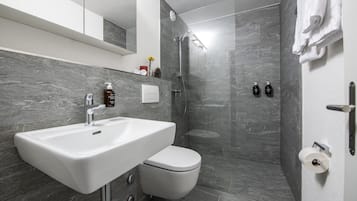 Une salle de bain moderne dotée d’un grand lavabo, de toilettes et d’un espace douche.