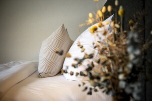 Una cama con dos almohadas y un arreglo decorativo de flores secas.