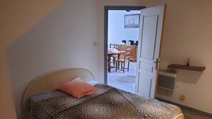 A bedroom with a bed, a bedside table, and a door leading to a dining area. - beautiful apartment 150m2, 4 bedrooms, 6 people (Noidans-le-Ferroux)