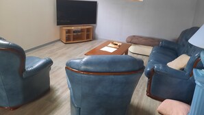 A living room with a flat-screen TV, a wooden entertainment unit, and a painting on the wall. - beautiful apartment 150m2, 4 bedrooms, 6 people (Noidans-le-Ferroux)