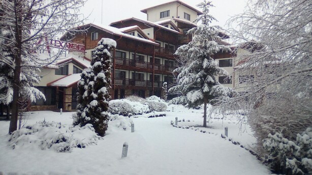 A snow-covered courtyard with a wooden building featuring balconies and a sign that reads "ANZIER".