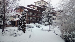 A snow-covered courtyard with a wooden building featuring balconies and a sign that reads "ANZIER".