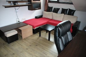 A compact living space with a sofa, a small table, a desk, and a chair.