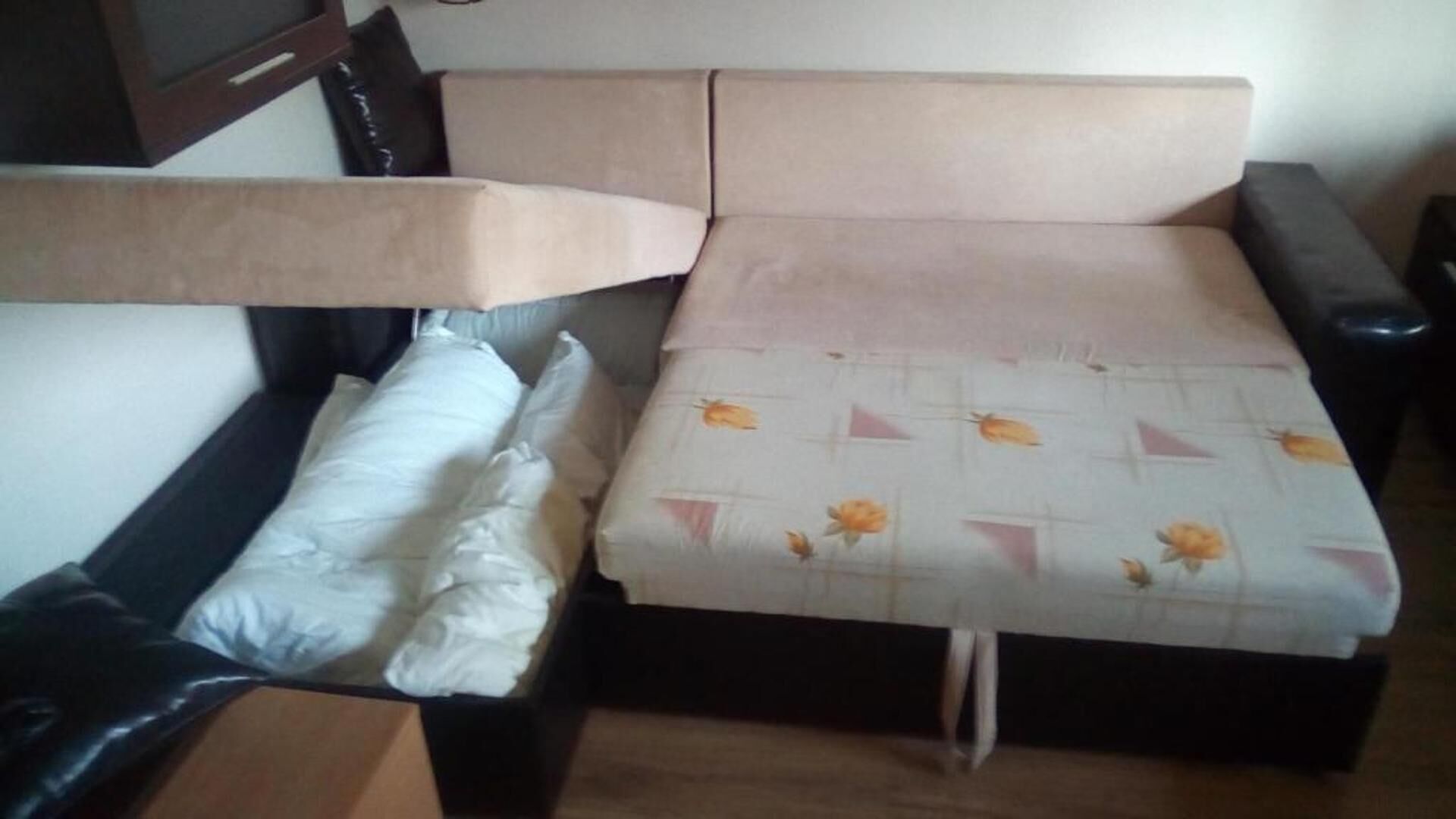 Un letto con cuscino bianco e copripiumino a motivi floreali.