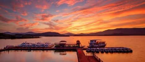 Un muelle frente al agua con barcos y un embarcadero que se adentra en aguas tranquilas.