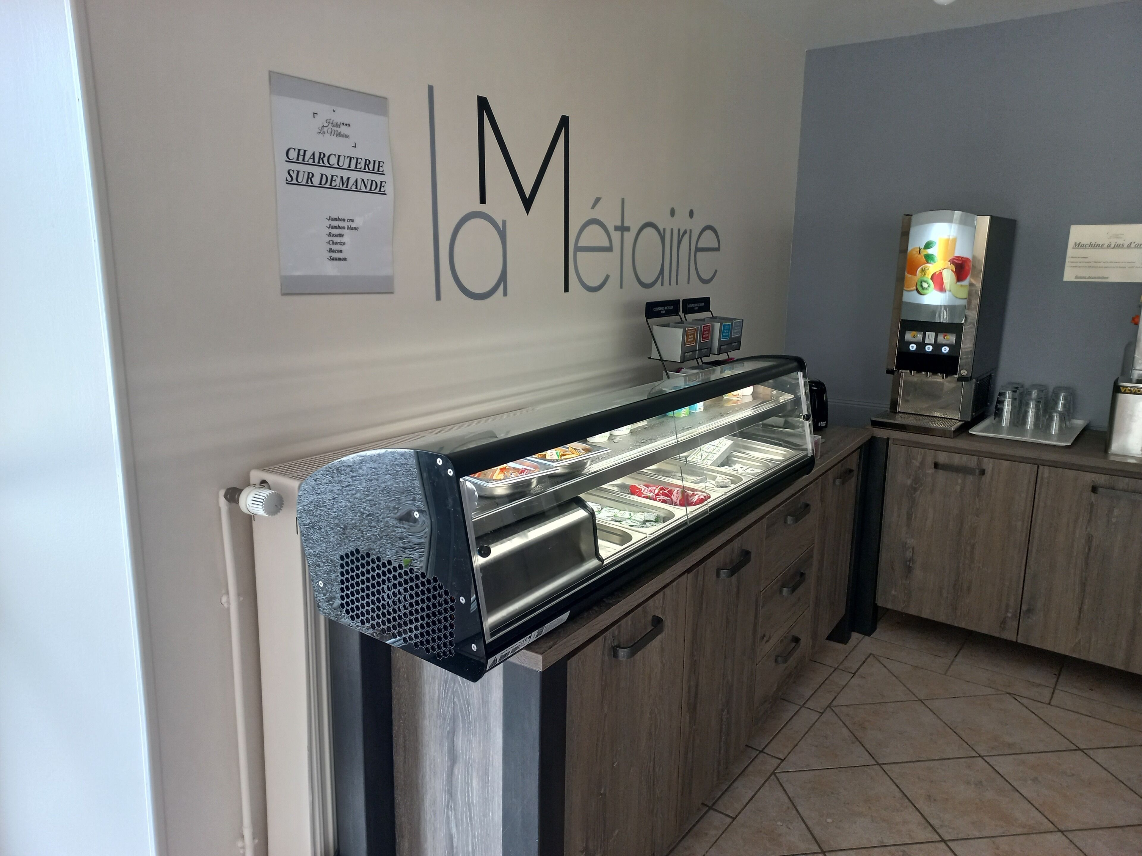 Una zona de menjar a disposició del públic, amb una vitrina de cristall, una màquina de cafè i un cartell amb el menú a dalt.