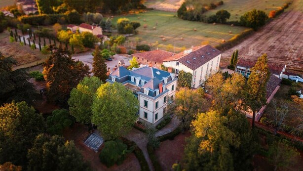 A large, two-story house with a prominent blue roof and white walls, surrounded by trees and a well-maintained garden. - Hôtel La Métairie (Cordes-sur-Ciel)