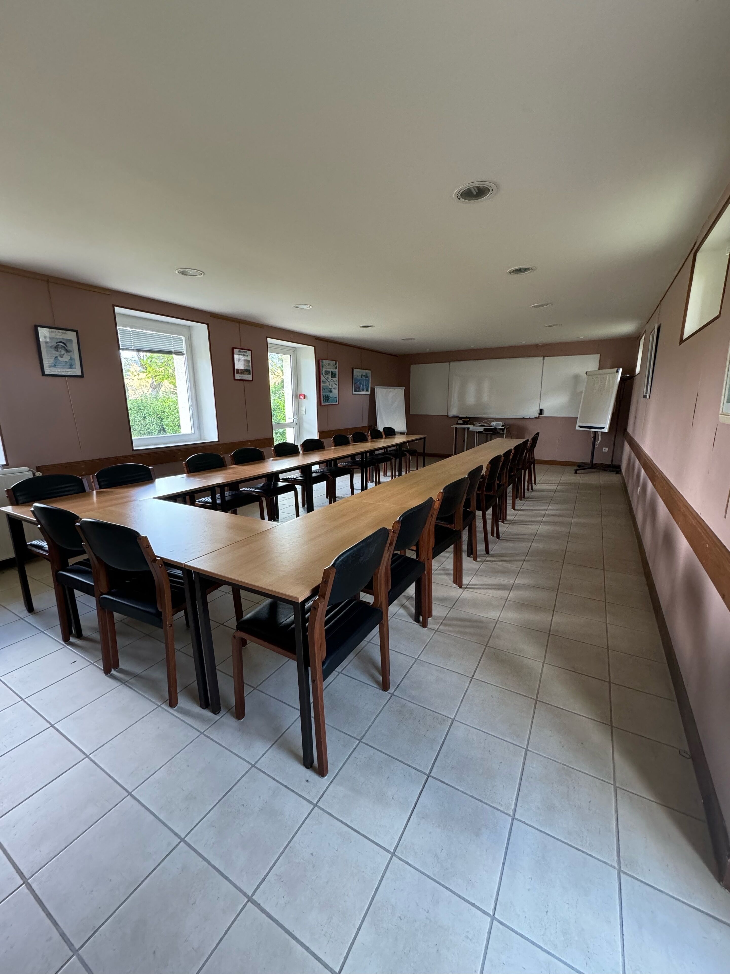 A conference room with long tables and chairs, whiteboards, and framed pictures on the walls.