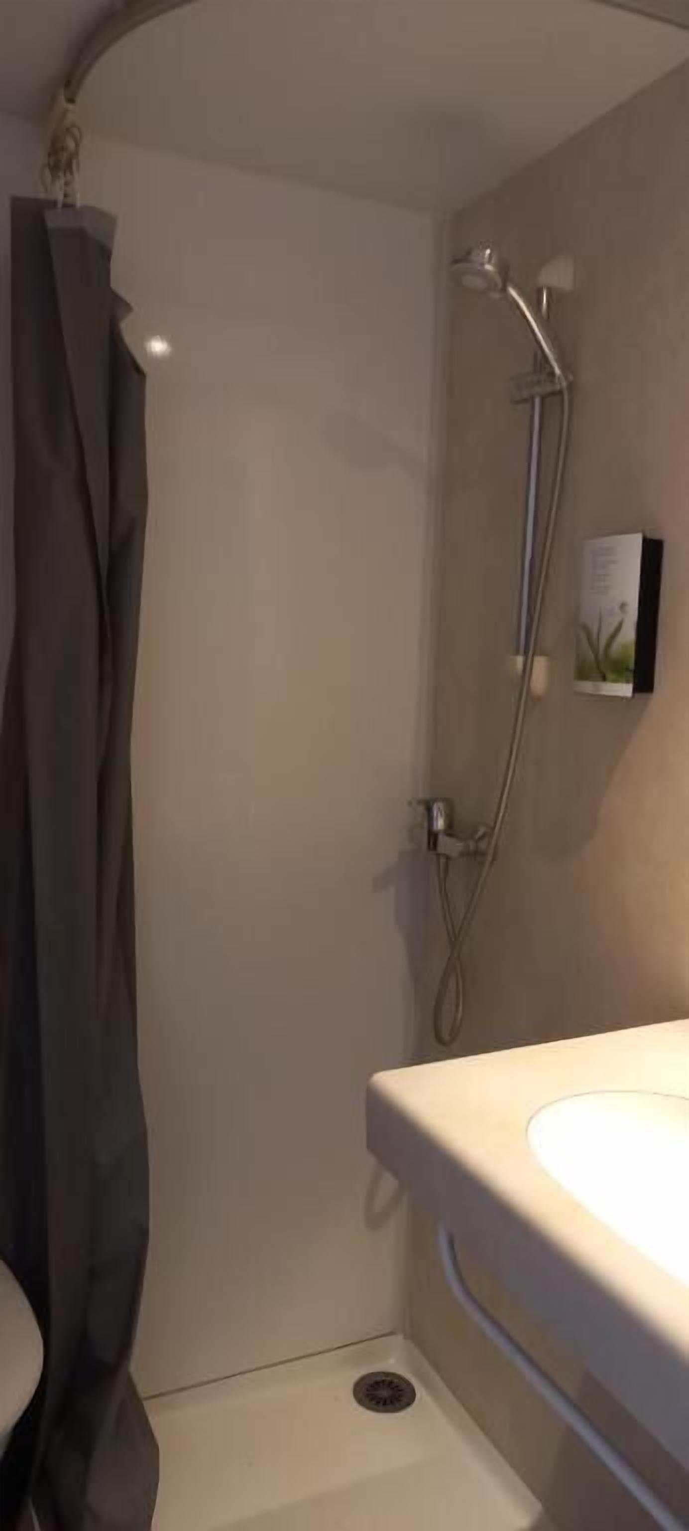 A bathroom with a shower, a toilet, and a sink.