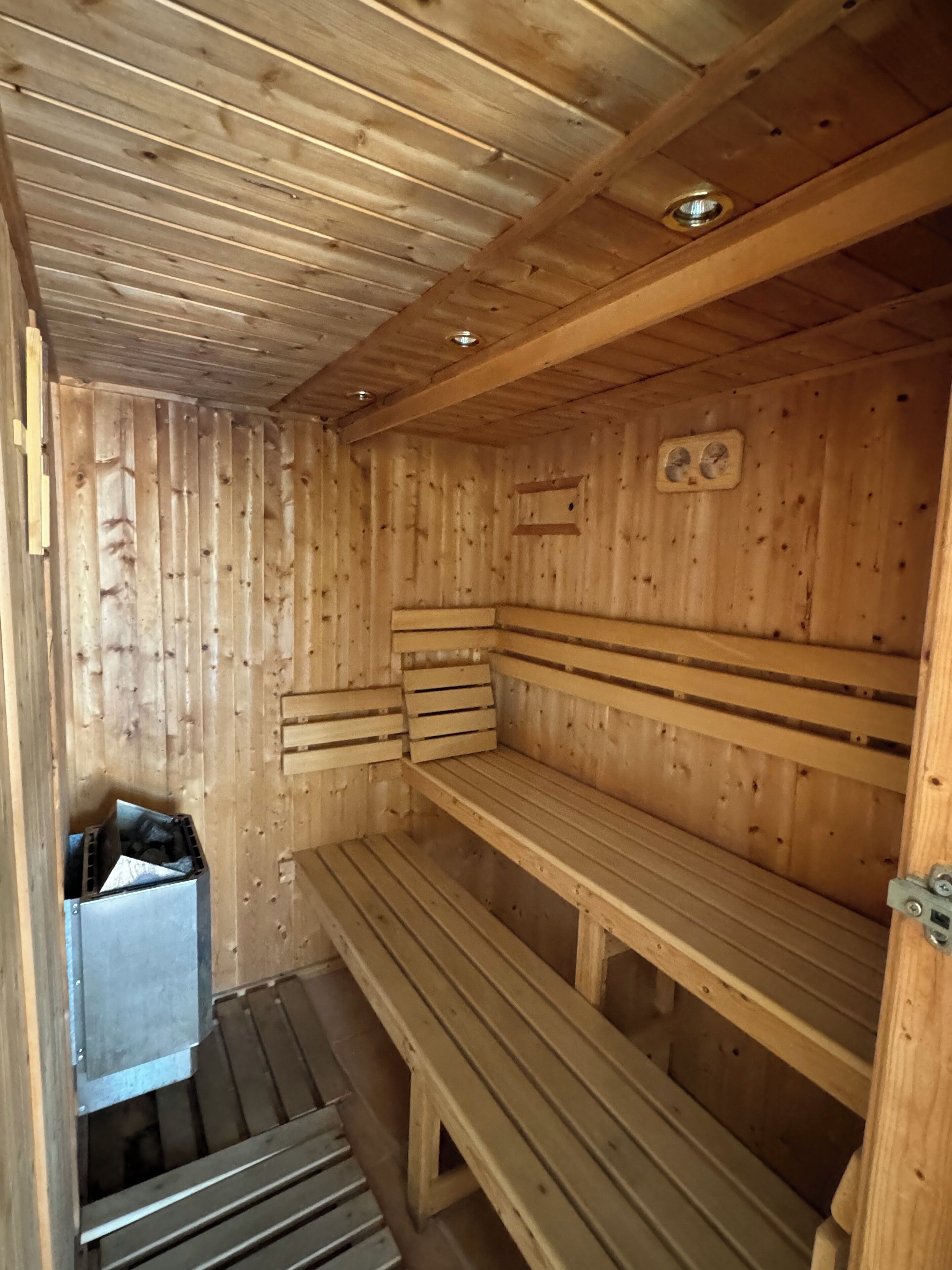 Eine Holzhütte als Sauna mit Bänken und einem kleinen Mülleimer.