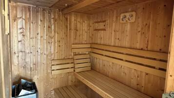 Una sauna de madera con bancos y un pequeño cubo de basura.