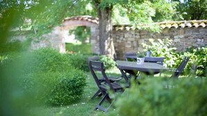 An outdoor dining area with a stone wall, a table, and chairs. - Hôtel La Métairie (Cordes-sur-Ciel)