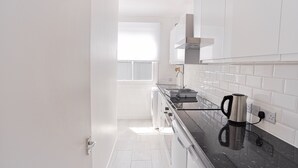 Eine moderne Küche mit weißen Schränken, einer schwarzen Arbeitsplatte und einem Wasserkocher auf der Arbeitsfläche.