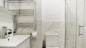 Ein modernes Badezimmer mit einem weißen Waschbecken, einer Toilette und einer Duschkabine aus Glas.