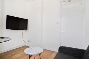 Relax in this cozy space with a flat-screen TV, small table, and comfortable sofa.