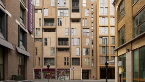 A multi-story building with a brick facade, multiple balconies, and a sign indicating 'Open every day 7am - 11pm'. - Charming 1-bed Apartment in Great Suffolk Street (London)