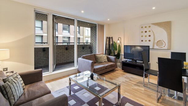 A modern living room with a glass coffee table, a sofa, a TV, and a dining area with chairs. - Charming 1-bed Apartment in Great Suffolk Street (London)