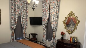 A bedroom with a bed, a TV, a dresser, a mirror, and curtains. - Holland Farmhouse Inn B & B (Holland)