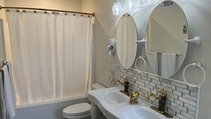 A bathroom with a shower curtain, a toilet, a sink with two basins, and two mirrors. - Holland Farmhouse Inn B & B (Holland)