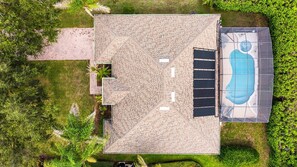 An aerial view of a house with a swimming pool, a covered patio, and a well-maintained lawn.