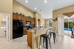 A modern kitchen with a central island, wooden cabinets, and a view of a swimming pool.