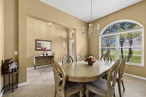 A dining area with a round table, chairs, and a chandelier.