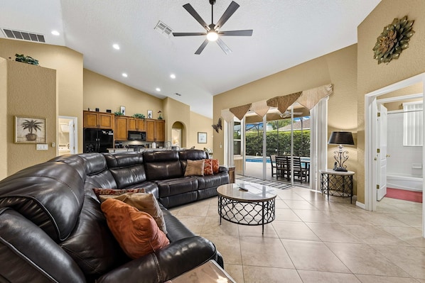 A spacious living area with a leather sofa, a coffee table, and a ceiling fan.