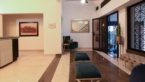 A modern hotel lobby with a reception desk, a green armchair, a blue bench, and a staircase. - PH 19 Guesthouse Hotel in Gazcue (Santo Domingo)