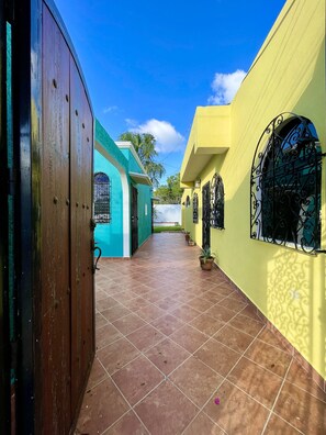 Um corredor com piso de azulejos, porta de madeira e paredes pintadas em tons de verde-água e amarelo.