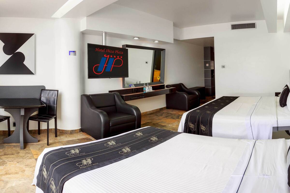 Une chambre d’hôtel avec deux lits, un bureau, une chaise, un canapé et un téléviseur.