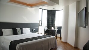 A hotel room with a large bed, a desk, and a chair.
