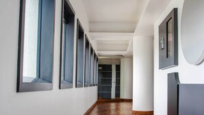 A long, narrow hallway with wooden flooring and large windows on one side.