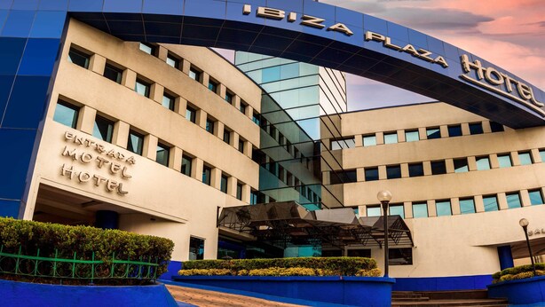 The exterior of the Ibiza Plaza Hotel with a modern design, featuring a prominent entrance and a clear sky in the background.